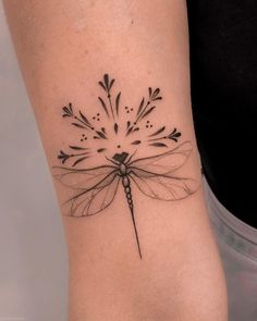 a black and white photo of a dragonfly tattoo on the right side of the arm