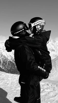 two snowboarders hugging each other in the snow