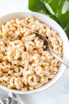 a white bowl filled with macaroni and cheese on top of a marble counter