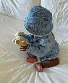 a small child sitting on top of a bed holding a teddy bear in his hands