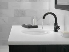 a bathroom sink with black faucet and soap dispenser