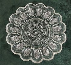 an ornate glass plate on a green velvet surface with white dots and circles in the center