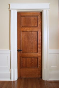 an empty room with a wooden door and hard wood flooring