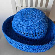 a blue crocheted hat sitting on top of a white chair