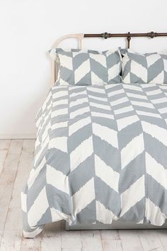 a bed with two pillows on top of it in a white and gray room next to a wooden headboard