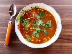 a white bowl filled with soup next to a spoon on top of a wooden table