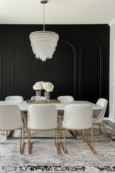 a dining room with black walls and white chairs