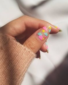 a woman's hand with colorful nail polish on it