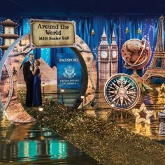 a man and woman are standing in front of a stage set with the words around the world on it