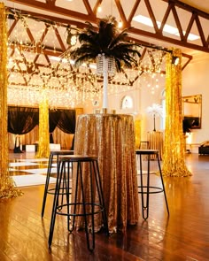 an event with gold and black decor, palm trees and lights hanging from the ceiling