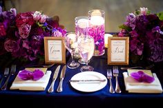 the table is set with purple flowers and silverware