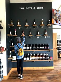 a person standing in front of a wall with bottles on it and shelves holding up their hands