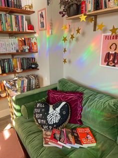 a green couch in front of a book shelf with books on it and a rainbow light coming through the window