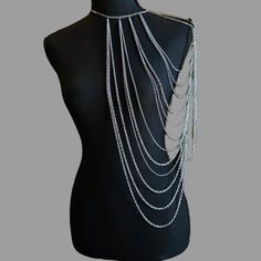 Introducing the majestic Silver Queen Body Chain, a stunning accessory that exudes elegance and strength. This remarkable body chain is meticulously designed to drape over the left shoulder, creating a captivating and empowering statement. Embrace your inner warrior queen and make a bold fashion statement with this extraordinary piece. The Silver Queen Body Chain features an intricate arrangement of looping chains of various sizes, symbolizing the unyielding spirit and resilience of a true queen. Its design reflects the perfect balance between elegance and strength, capturing the essence of a powerful and fearless leader. Crafted with meticulous attention to detail, the Silver Queen Body Chain is a testament to the craftsmanship and quality that goes into each piece. It is made from high-q Full Body Jewellery, Silver Adjustable Body Chain For Festivals, Bohemian Body Jewelry With Chain Strap For Festivals, Bohemian Body Chain With Chain Strap For Festivals, Elegant Clavicle Chain Body Jewelry For Festivals, Silver Body Chain With Chain Strap For Evening, Bohemian Body Jewelry With Chain Strap, Silver Chain Strap Body Chain For Evening, Elegant Clavicle Chain Body Chain For Festivals