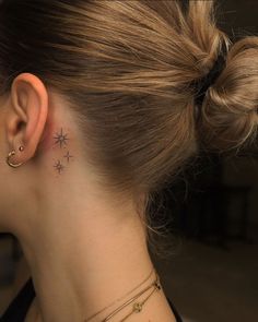 a woman with a small star tattoo on her left side behind the ear is looking down