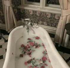 a bathtub filled with water and pink flowers