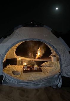 the inside of a tent is lit up at night with candles and food in it