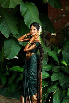 a woman in a green and gold sari with her hands on her face, posing for the camera