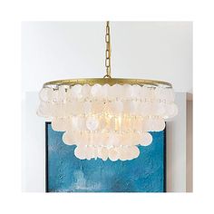 a chandelier hanging from the ceiling in front of a blue wall and painting