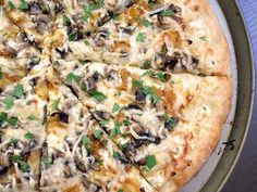 a pizza with cheese, mushrooms and parsley on it is sitting on a pan