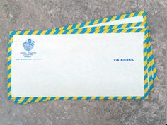 two blue and yellow striped envelopes sitting on top of a cement floor next to each other