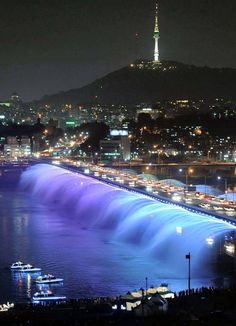 a bridge that is lit up at night with water gushing out the side and lights on