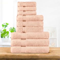 a stack of pink towels sitting on top of a wooden table next to a potted plant