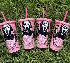 three pink cups with black and white designs on them sitting in the grass next to each other