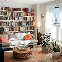 a living room filled with furniture and lots of books on the shelves in front of a window