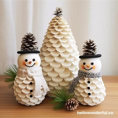 three snowmen made out of pine cones on a table