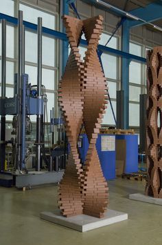 a sculpture made out of wooden blocks in a factory area with large windows behind it