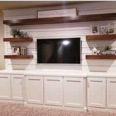 a flat screen tv mounted to the side of a wall with wooden shelves below it