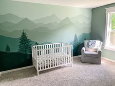 a baby's room with a mountain mural on the wall and a crib