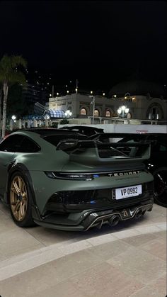 a green sports car parked in front of a building at night with its lights on