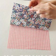 someone is cutting up fabric with scissors on a white tablecloth that has flowers and gingham