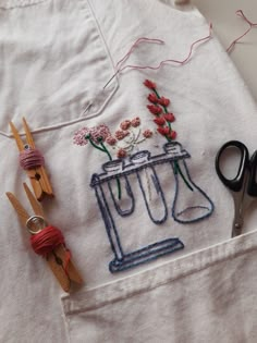 a pair of scissors sitting on top of a piece of cloth next to some flowers