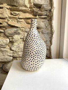 a blue and white vase sitting on top of a table next to a stone wall