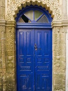 an old building with two blue doors and ornate carvings on the front door is shown