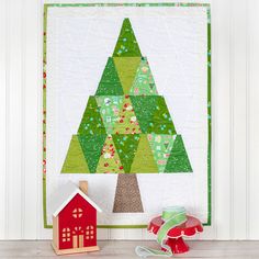 a quilted christmas tree next to a red toy house and green trimmings