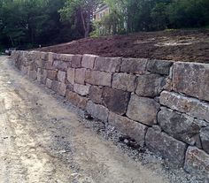 a large stone wall next to a dirt road