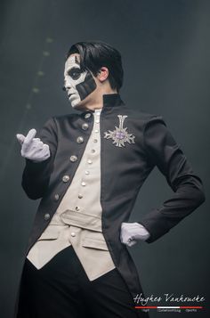 a man dressed in black and white with his face painted like a skeleton is standing on stage