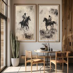 two paintings hang on the wall above a table with chairs and a potted cactus