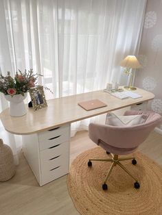 a desk with a chair, laptop and flowers on it in front of a window