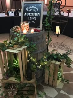 a wine barrel with lights and greenery around it for an auction items display at a wedding