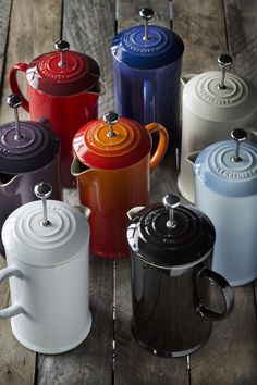 many different colored pots and pans on a wooden table