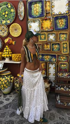 a woman standing in front of a wall covered with plates