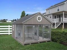 a dog kennel in the middle of a yard with a fence and two houses behind it