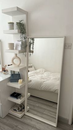 a bedroom with a large mirror on the wall next to a white bed and nightstand