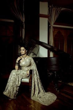 a woman is sitting on a chair in front of a piano and posing for the camera