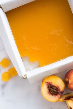 two peaches and one piece of apricot in a white bowl